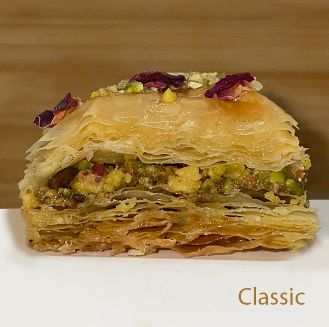 Layered classic baklawa with pistachios and dried rose petals on a wooden background