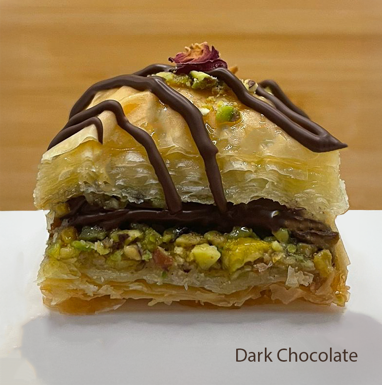 Layered Dark Chocolate flavoured baklawa with pistachios and dried rose petals on a wooden background
