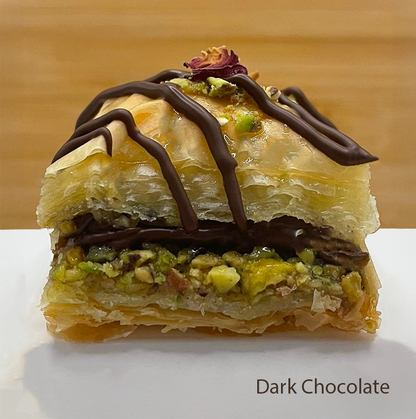 Layered Dark Chocolate flavoured baklawa with pistachios and dried rose petals on a wooden background