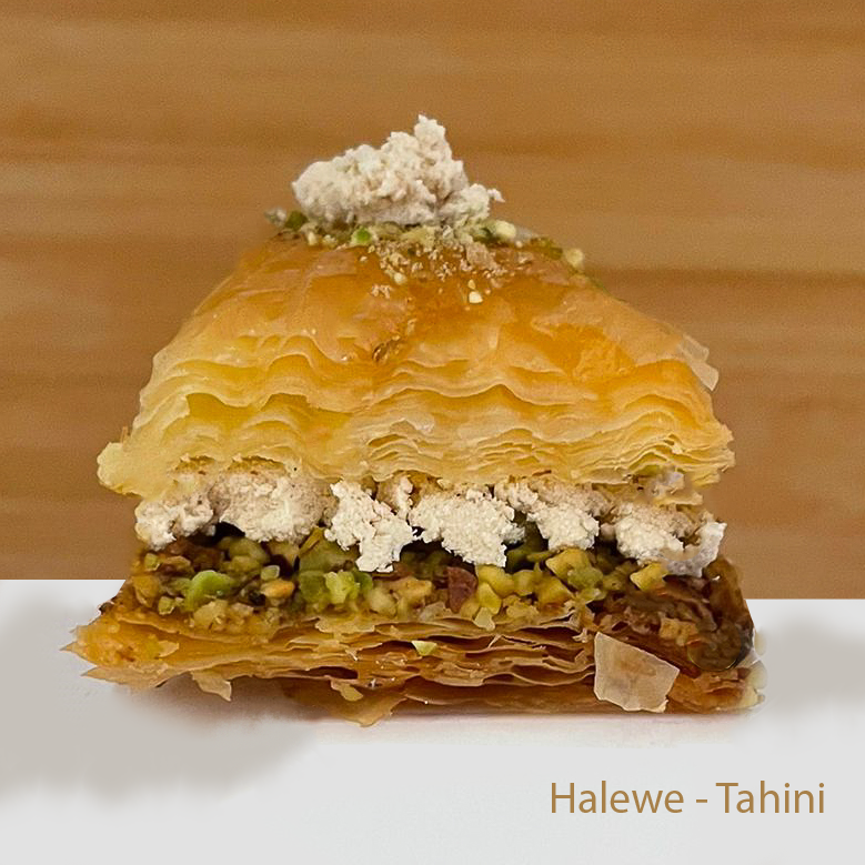 Layered halewe baklawa with pistachios and dried rose petals on a wooden background