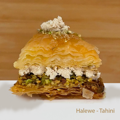 Layered halewe baklawa with pistachios and dried rose petals on a wooden background