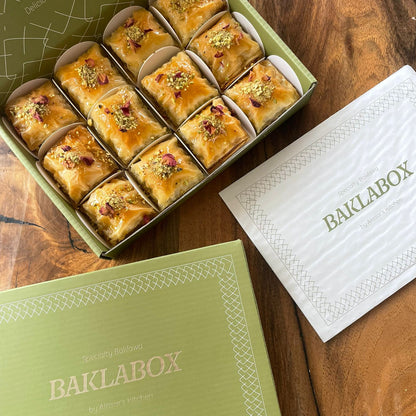 A 'BAKLABOX' full of classic baklawa on a wooden table