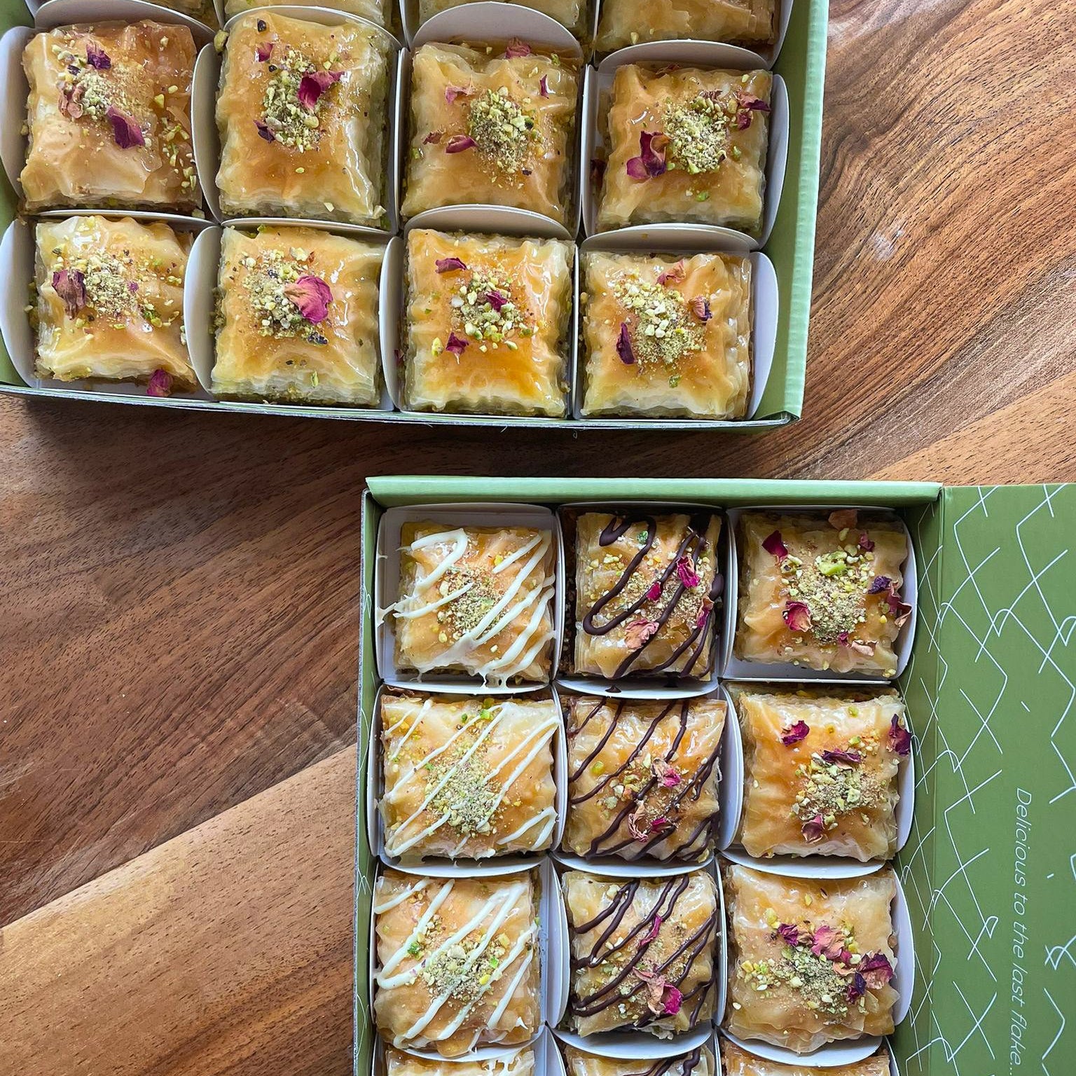Two boxes of assorted baklava on a wooden surface
