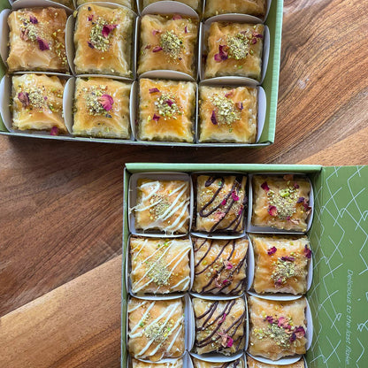 Two boxes of assorted baklava on a wooden surface